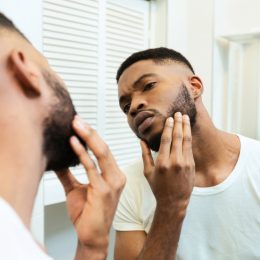 Man examining his face in the mirror.