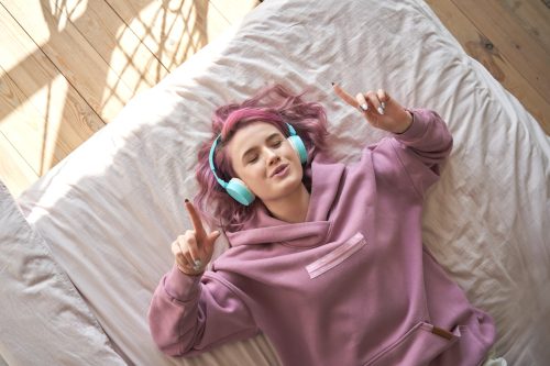 young teen with pink hair listening to music