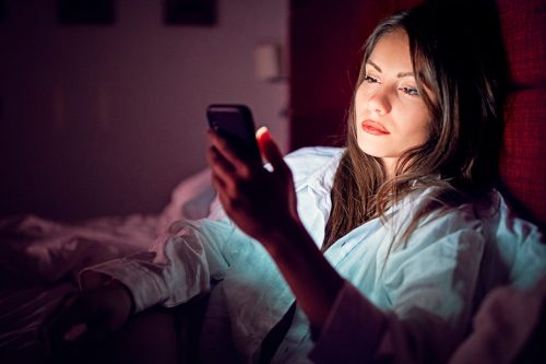 Woman is texting in bed at night