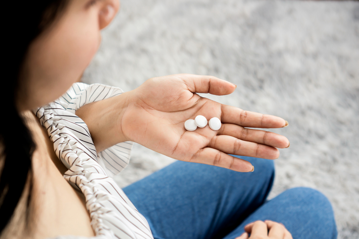 Woman holding pills in the palm of her hand.