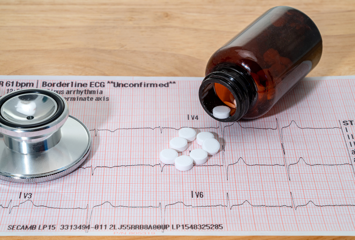 ECG test and pills spilling out of a container.
