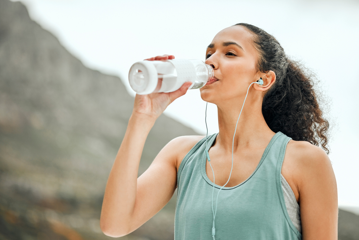 Woman in fitness gear drinking water.