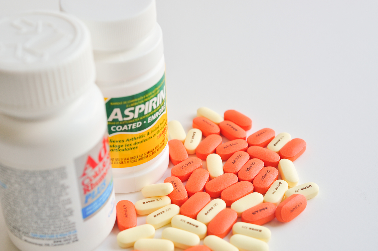 Aspirin and Advil pill bottles and pills.