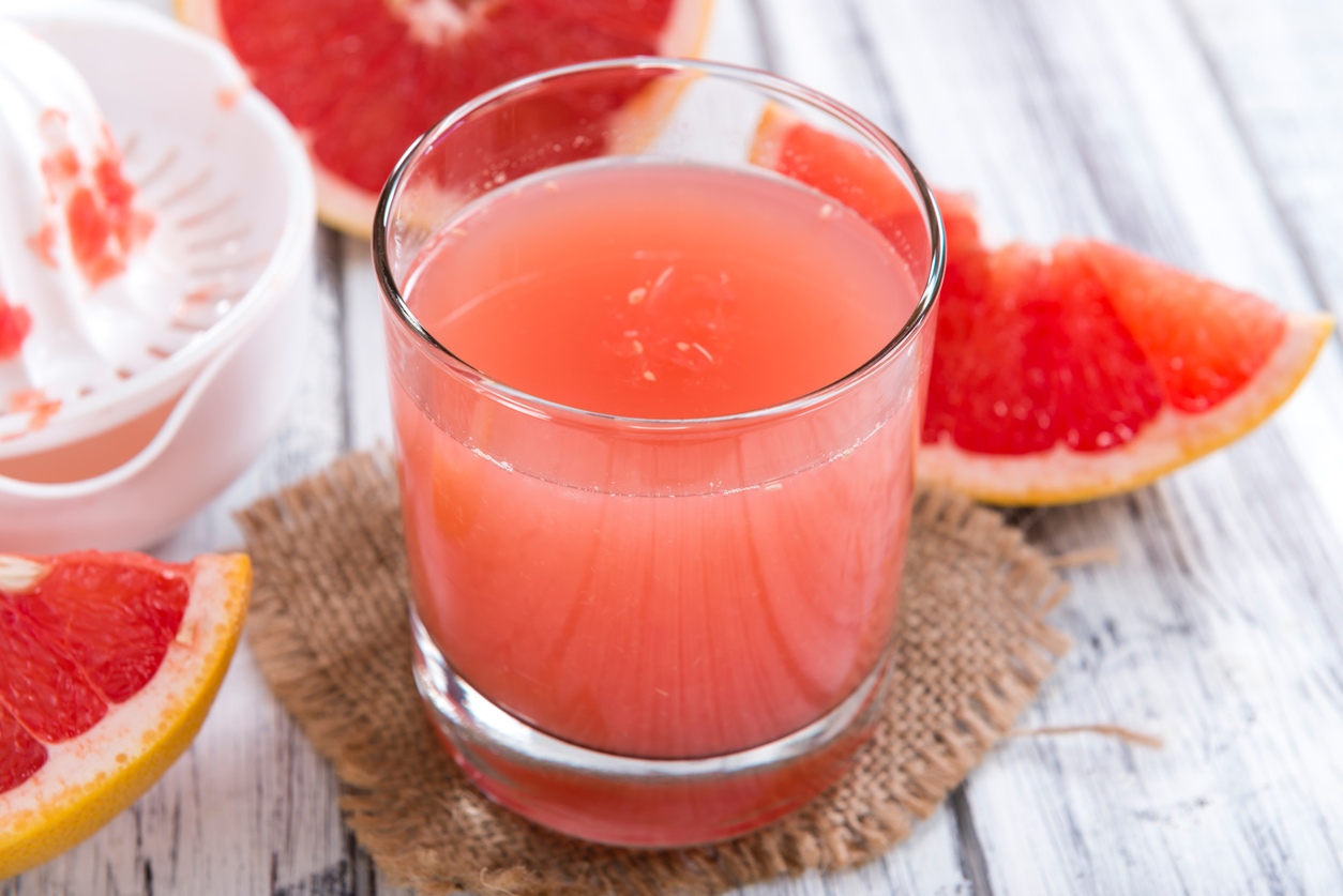 Slices of grapefruit and a glass of grapefruit juice.