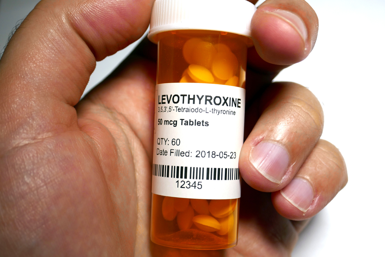 A hand holding a bottle of levothyroxine.