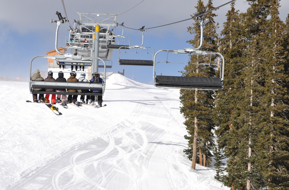 A group of skiers riding a chair lift up a mountain
