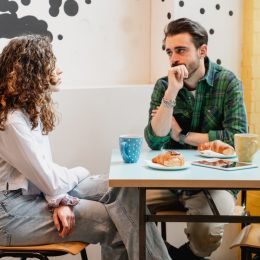 Young couple sitting at table in a cafe talking with serious faces.