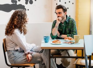 Young couple sitting at table in a cafe talking with serious faces.