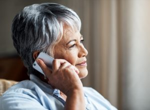 Cropped shot of a senior woman looking thoughtful while using her cellphone at home