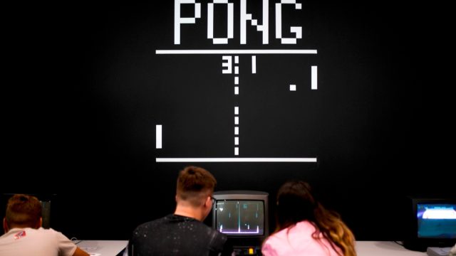 Visitors play the retro game "Pong" at the Video games trade fair Gamescom in Cologne.