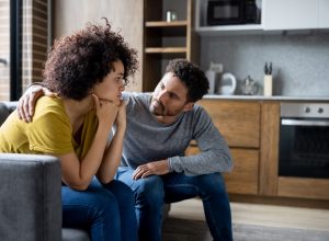 man comforting his girlfriend at home while she is looking upset - lifestyle concepts
