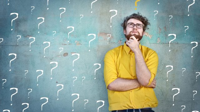 man looking doubtful with question marks behind him