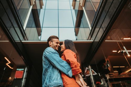 man and woman hugging in front of building