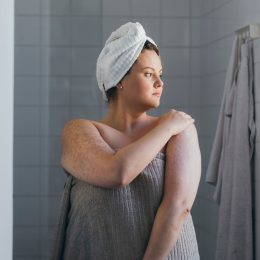 woman applying body lotion after a shower in the morning