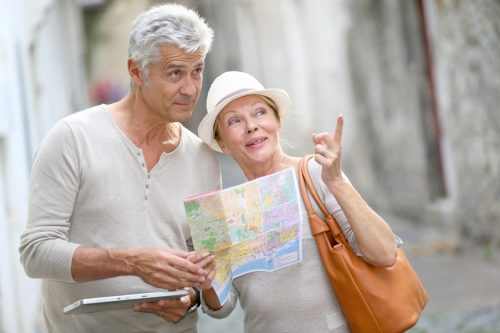 A mature mand and woman looking at a map and pointing while traveling