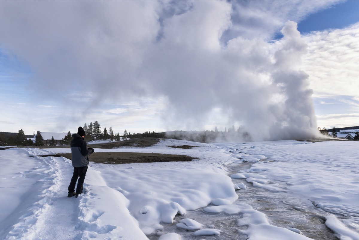 man at old faithful in winter