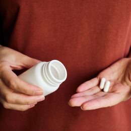 A woman pours pills or vitamins from a jar onto her hand. Taking vitamins or medications. The concept of health care, medicine, pharmacies, disease prevention. A jar with pills or vitamins in the hand