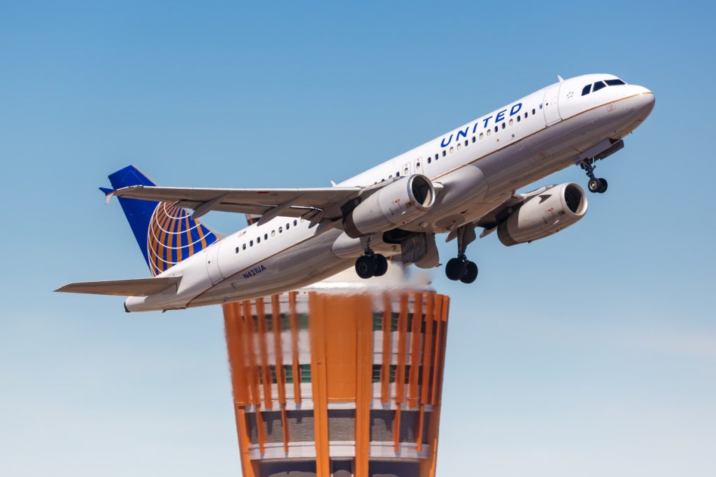 A United Airlines flight taking off from the airport with an air traffic control tower in the background