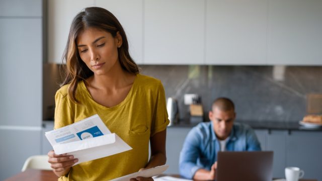 woman at home looking worried getting bills in the mail - domestic life concepts