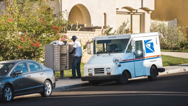 US Postal Service worker delivers mail to a community mailbox in Los Angeles, California