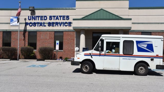 King of Prussia, PA/USA-April 7, 2020: United States Post Office truck parks outside the post office building to pick up mail during the COVID-19 virus, since they are considered essential business.