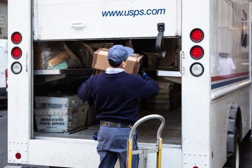 Thành phố New York, Hoa Kỳ - ngày 4 tháng 2 năm 2019: Một xe tải chở đầy nhân viên Bưu điện USPS đậu trên đường phố trung tâm Thành phố New York