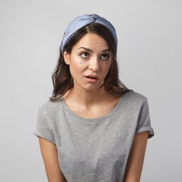 Funny emotional young Caucasian woman wearing gray top and headscarf grimacing, rolling her eyes, expressing annoyance