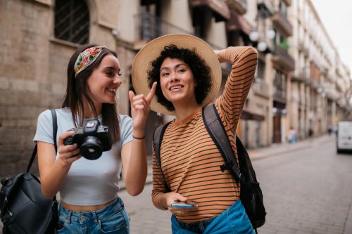 Two women walking down the street with cameras on a trip