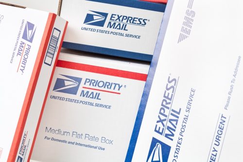 Cận cảnh các Hộp và Phong bì Chuyển phát nhanh của Dịch vụ Bưu chính Hoa Kỳ (USPS) xếp chồng lên nhau.  Vận chuyển USPS do chính phủ Hoa Kỳ xử lý và vận chuyển và chuyển phát nhanh, ưu tiên và thư tiêu chuẩn trên toàn quốc và các quốc gia khác trên thế giới.