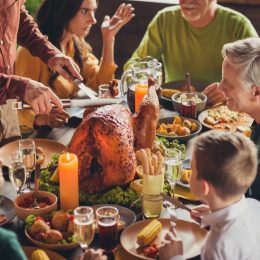 Cropped photo of family meeting, served table thanks giving dinner two knives slicing stuffed turkey meal living room indoors