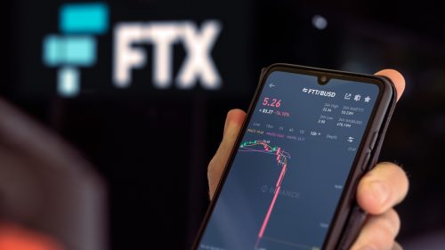 Hands holding photo with FTX crypto app.