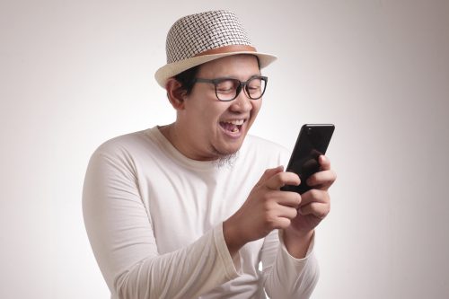 man laughing at his phone after reading the group chat