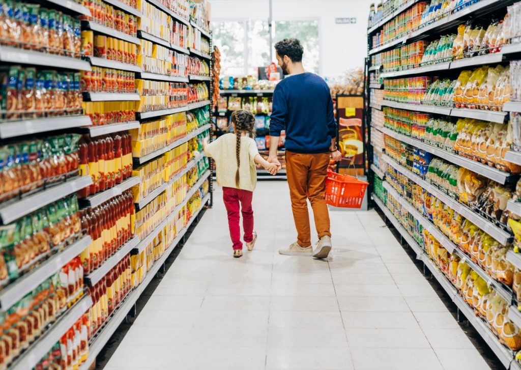 Father and daughter shopping at grocery store. Family is at supermarket. They are holding hands while walking at aisle.