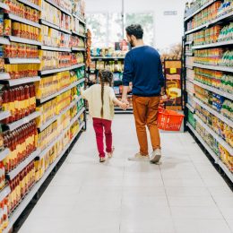 Father and daughter shopping at grocery store. Family is at supermarket. They are holding hands while walking at aisle.