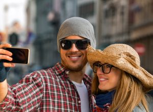 A young tourist couple wearing hats and taking a selfie.