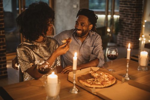 Young couple having romantic dinner at home. Eating pizza and drinking wine. 