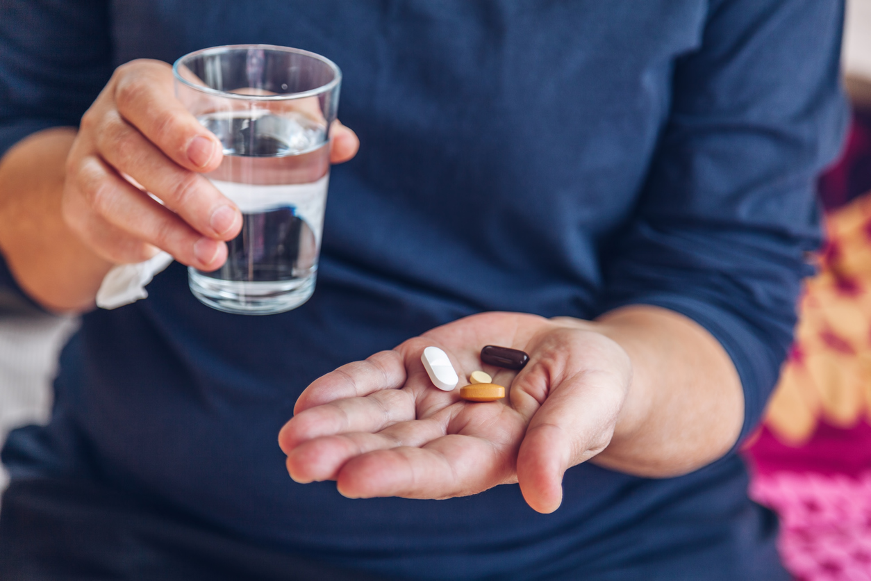 Woman holding medication and a glass of water. 