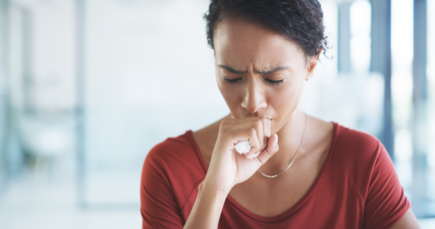 Woman coughing and covering her mouth.