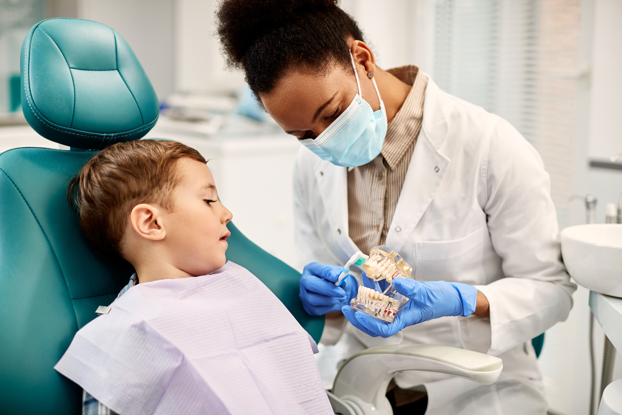 Dentist talking to child in dentist chair. 