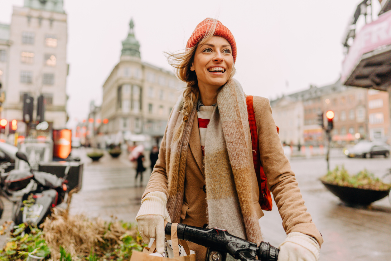 Photo of a smiling young woman running errands on her bicycle all over the city