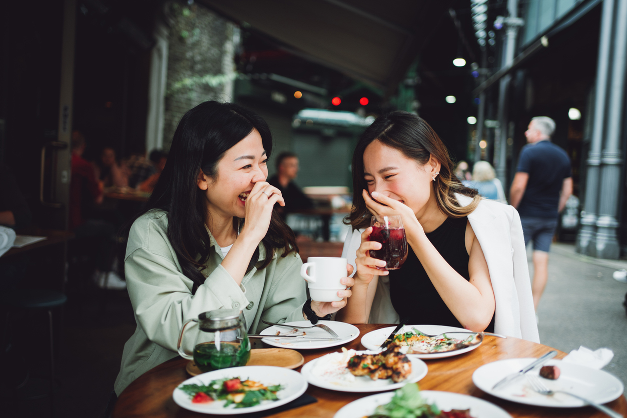 two asian women laughing and eating lunch together
