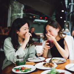 two asian women laughing and eating lunch together