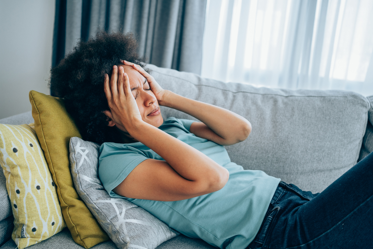 Woman lying on couch feeling sick.