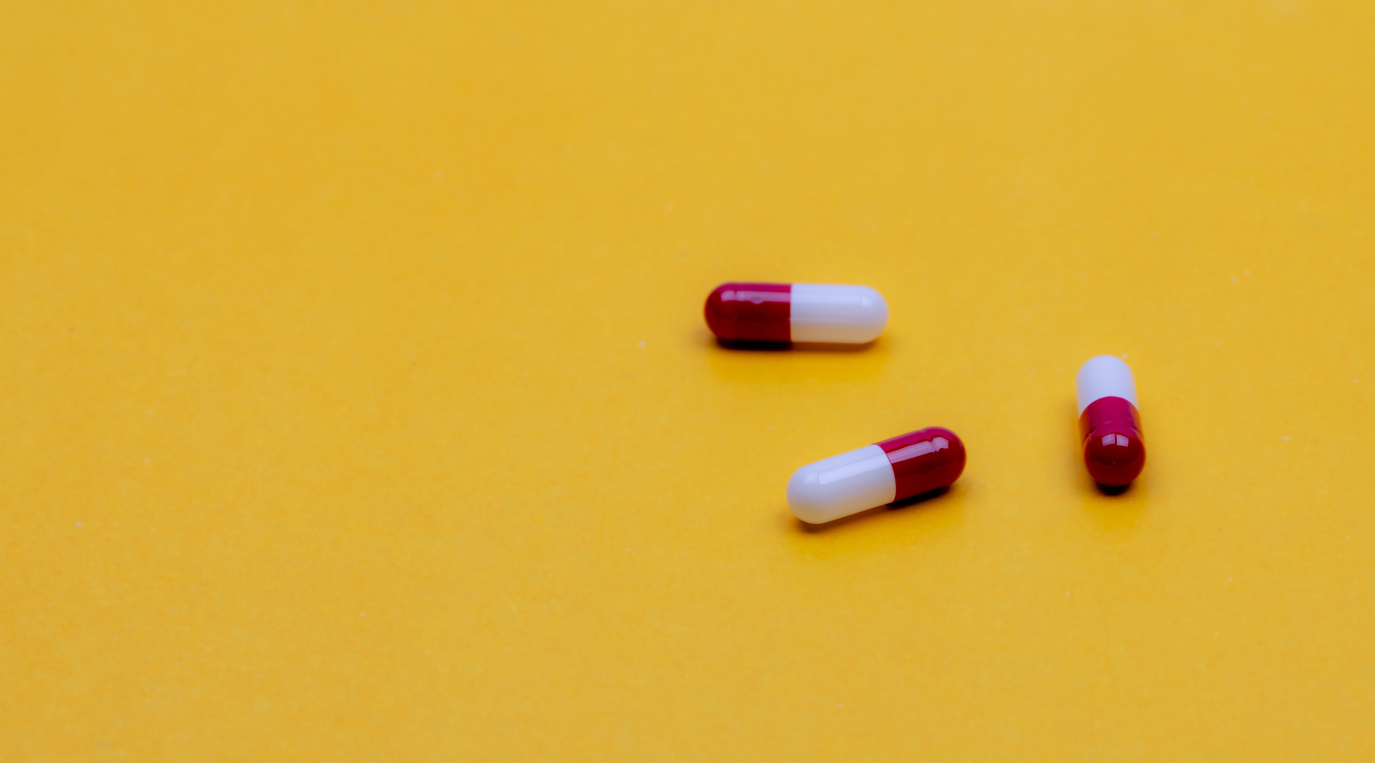 Red and white capsules on a yellow background. 