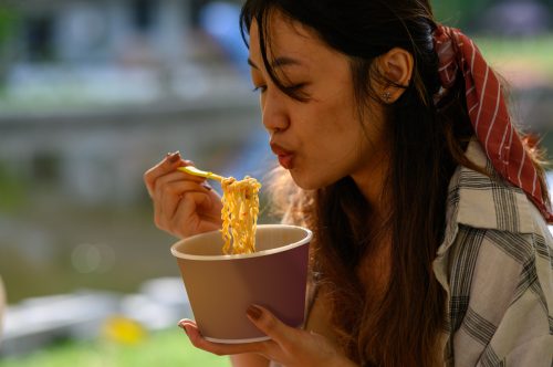 young asian woman eating ramen