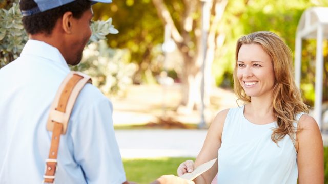 mail carrier delivering letter to smiling woman