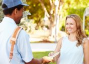 mail carrier delivering letter to smiling woman