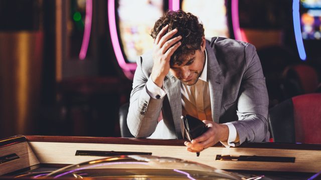 A man looking into his empty wallet at a casino