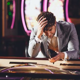 A man looking into his empty wallet at a casino
