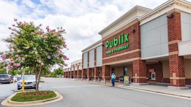 Side view of a Publix grocery store with a pink flowering tree in front.